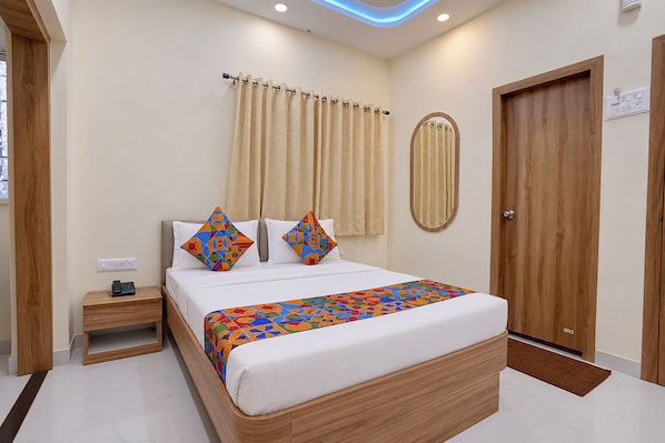 A hotel room with a bed, bedside table, and a wooden wardrobe.