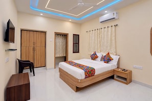 A bedroom with a bed, bedside table, TV, wardrobe, and an air conditioning unit.