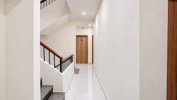 Un interior moderno con una escalera, una puerta de madera y un suelo blanco e impecable.