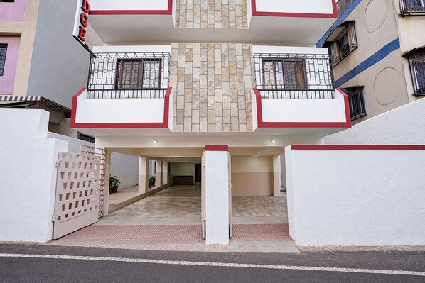 Un immeuble résidentiel à plusieurs étages doté d’une cour intérieure, de balcons avec des garde-corps en métal et d’une entrée fermée par un portail.