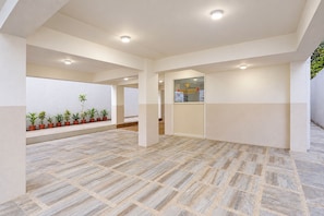 A spacious interior with a tiled floor, potted plants, and a reception area with a glass door. - FabHotel Parinda Lodging (Pune)