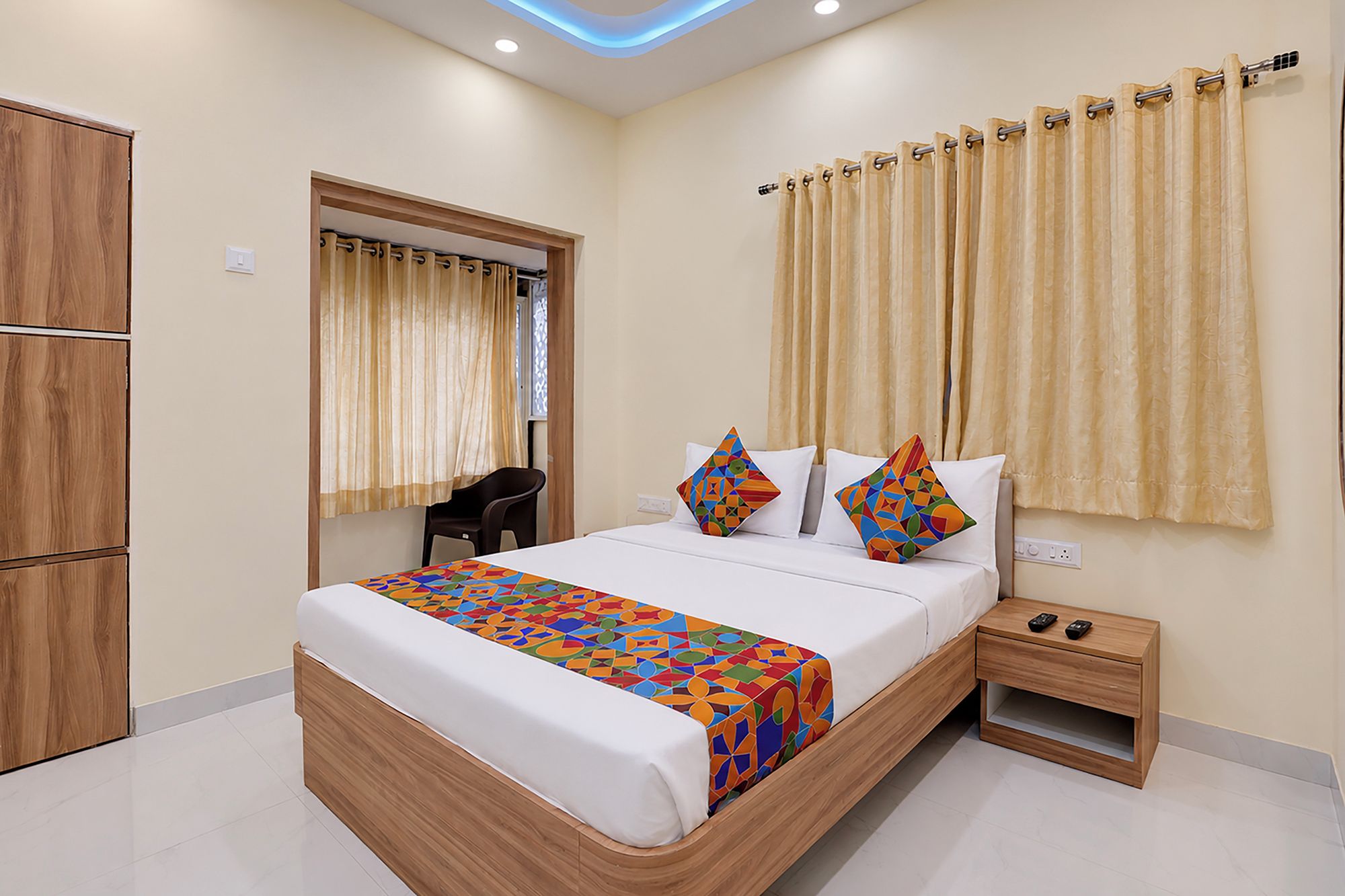 A hotel room with a bed, bedside table, and a wardrobe.