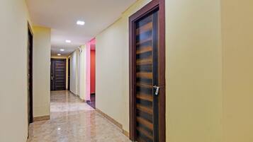 Un pasillo con puertas, piso de baldosas e iluminación empotrada en el techo.