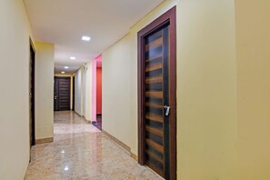 Un pasillo con puertas, piso de baldosas e iluminación empotrada en el techo.