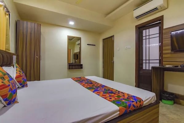 A hotel room with a bed, a mirror, a wardrobe, and an air conditioning unit. - FabHotel Sunshine Ii (Barasat)