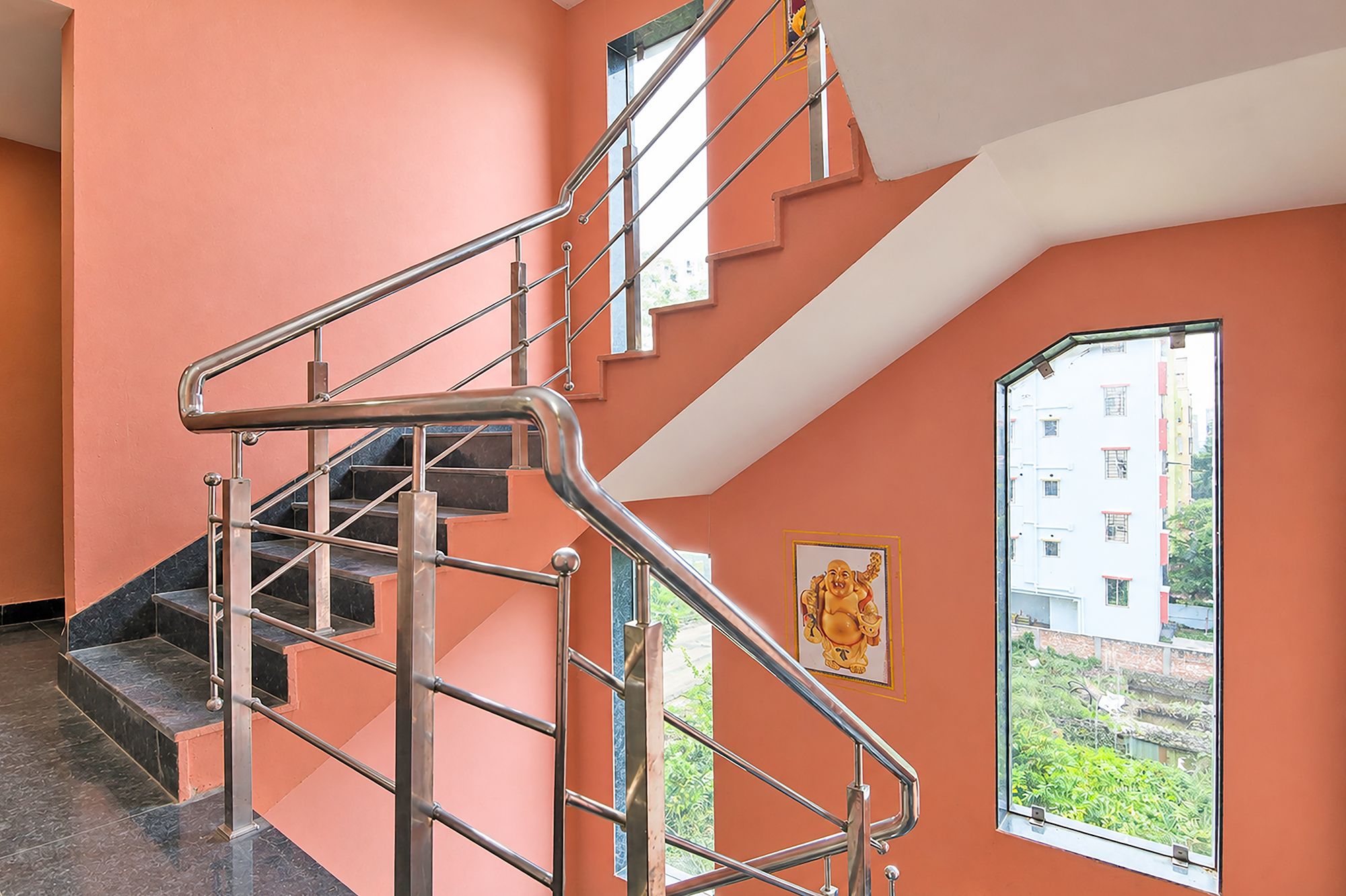 Una escalera con barandillas de metal y vistas de un edificio a través de una ventana.