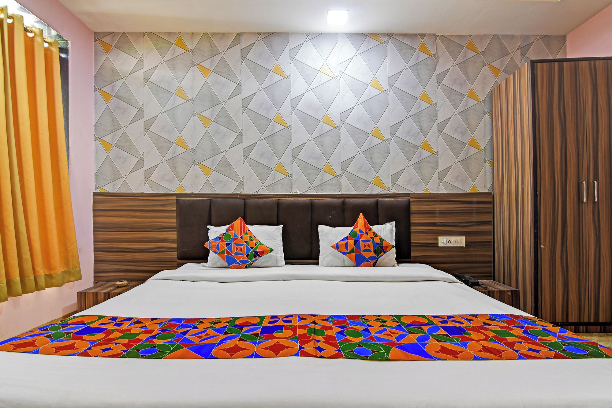 Una habitación de hotel con cama, cabecera, armario y pared con diseño.