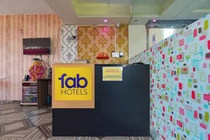 Una taquilla de recepció amb un cartell de 'fab hotels', una paret amb un disseny i una paret colorida amb formes geomètriques.