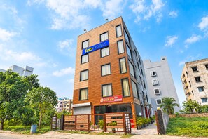 Un hotel de varios pisos con un llamativo letrero que dice 'HOTELES', un restaurante con un letrero rojo y una entrada con portón.