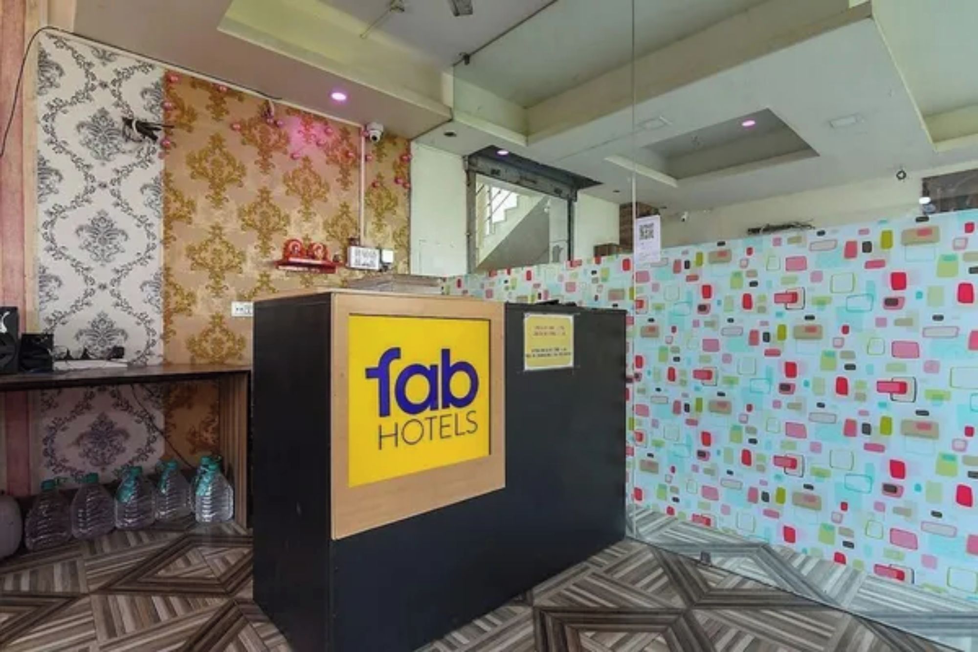 A hotel reception desk with a sign reading 'fab HOTELS' and a wall covered with colorful sticky notes.