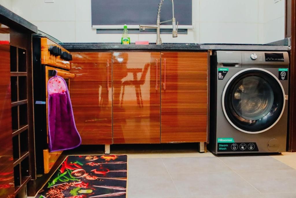 Cocina compacta con lavadora, armarios de madera y una toalla morada colgada en la puerta.