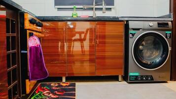 Cocina compacta con lavadora, armarios de madera y una toalla morada colgada en la puerta.