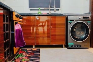 Cocina compacta con lavadora, armarios de madera y una toalla morada colgada en la puerta.