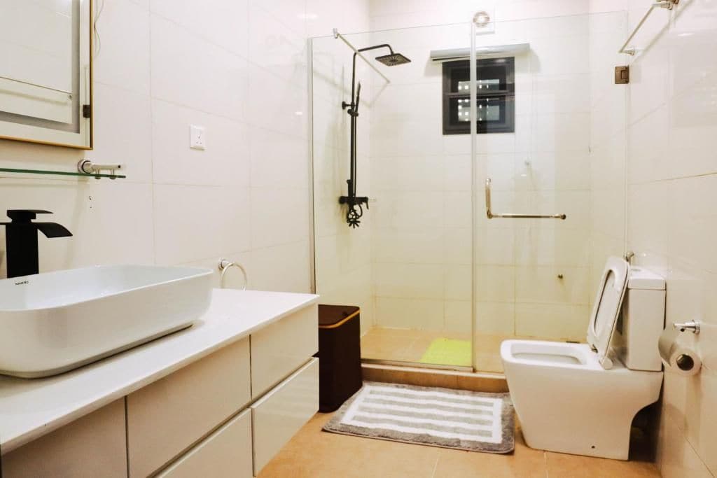 Un baño moderno con ducha de vidrio, lavamanos blanco y un inodoro.