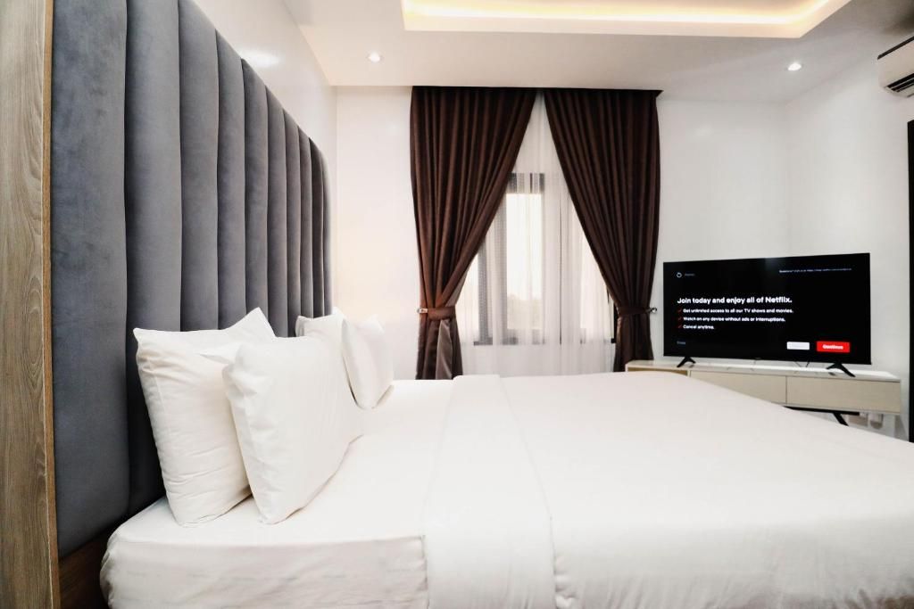 Een moderne hotelkamer met een groot bed, een flatscreen televisie en uitzicht op de omgeving.