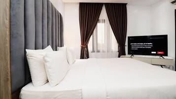 Een moderne hotelkamer met een groot bed, een flatscreen televisie en uitzicht op de omgeving.