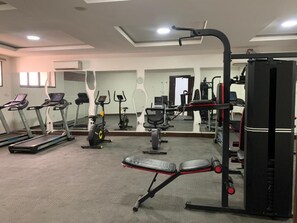 A gym with treadmills, a bench press, and weight machines. - Homies Apartment (Lekki)