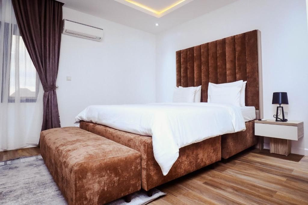 A modern bedroom with a large bed, a bedside table, and a bench.