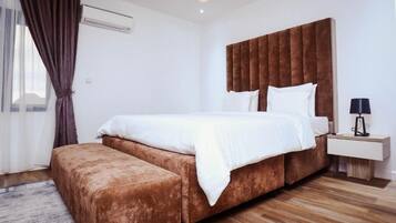 A modern bedroom with a large bed, a bedside table, and a bench.