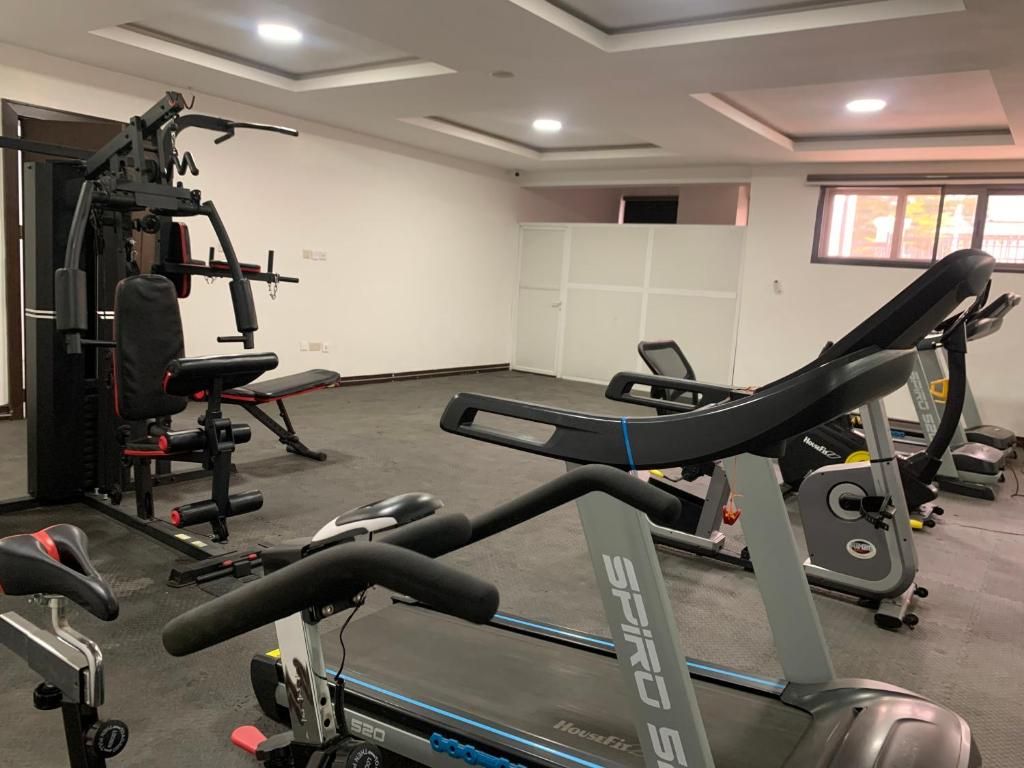 A gym with cardio equipment, weight machines, and a wall-mounted exercise bike.