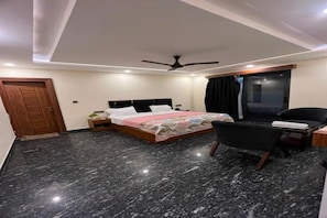 Habitación de hotel con cama, escritorio, silla, ventilador de techo y ventana con cortinas.