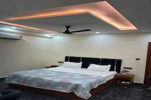 A modern bedroom with a bed, a ceiling fan, and a nightstand with a vase. - FabHotel Delluna (Greater Noida)