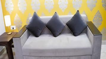 A grey sofa with three dark cushions against a yellow patterned wall.