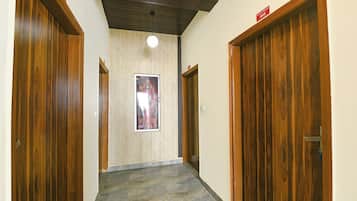 Un pasillo con puertas de madera, piso de baldosas y un cartel en la pared.