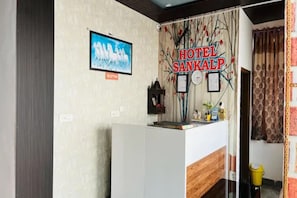 A reception area with a 'HOTEL SANKALP' sign, a framed picture, and a reception desk.