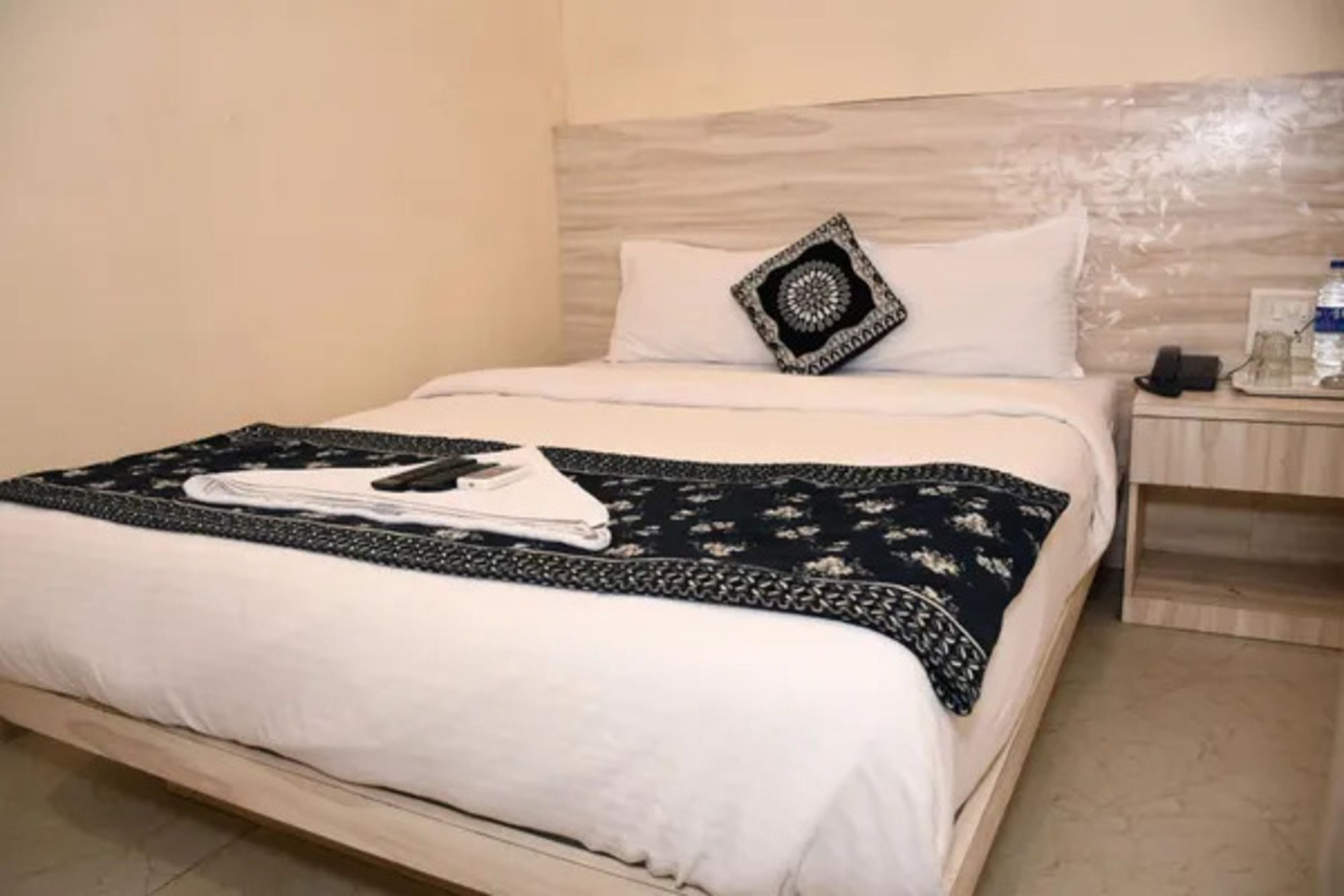 Una cama bien hecha con una colcha blanca y un plaid blanco y negro.