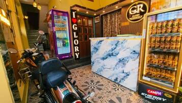 A hotel lobby with a marble reception desk, vending machines, and a motorcycle parked in the corner.