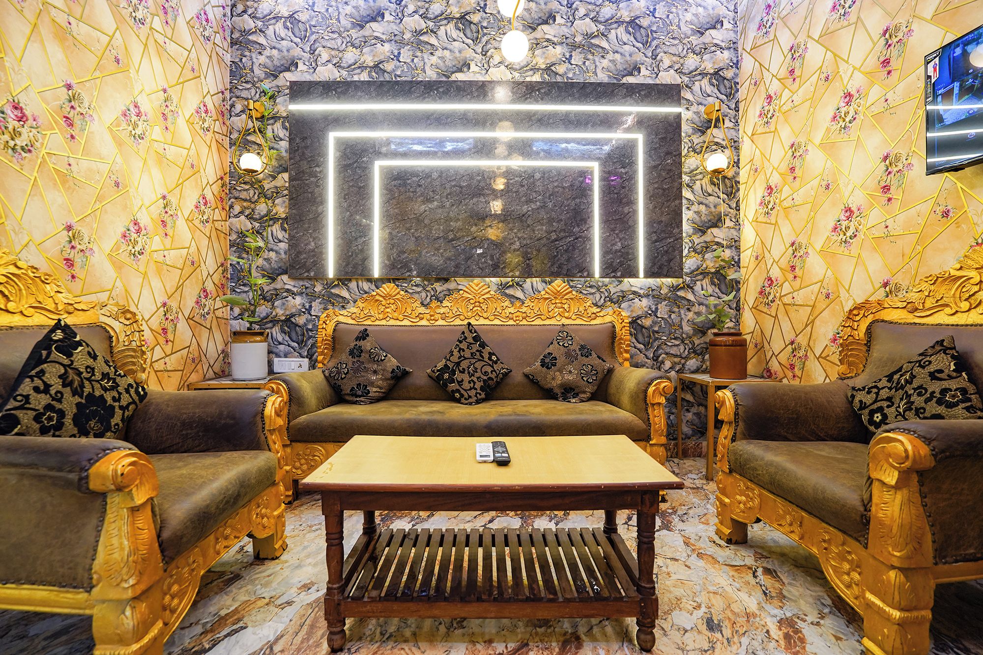 Un elegante área de descanso con pared de diseño de mármol, un televisor de pantalla plana grande y muebles decorados.