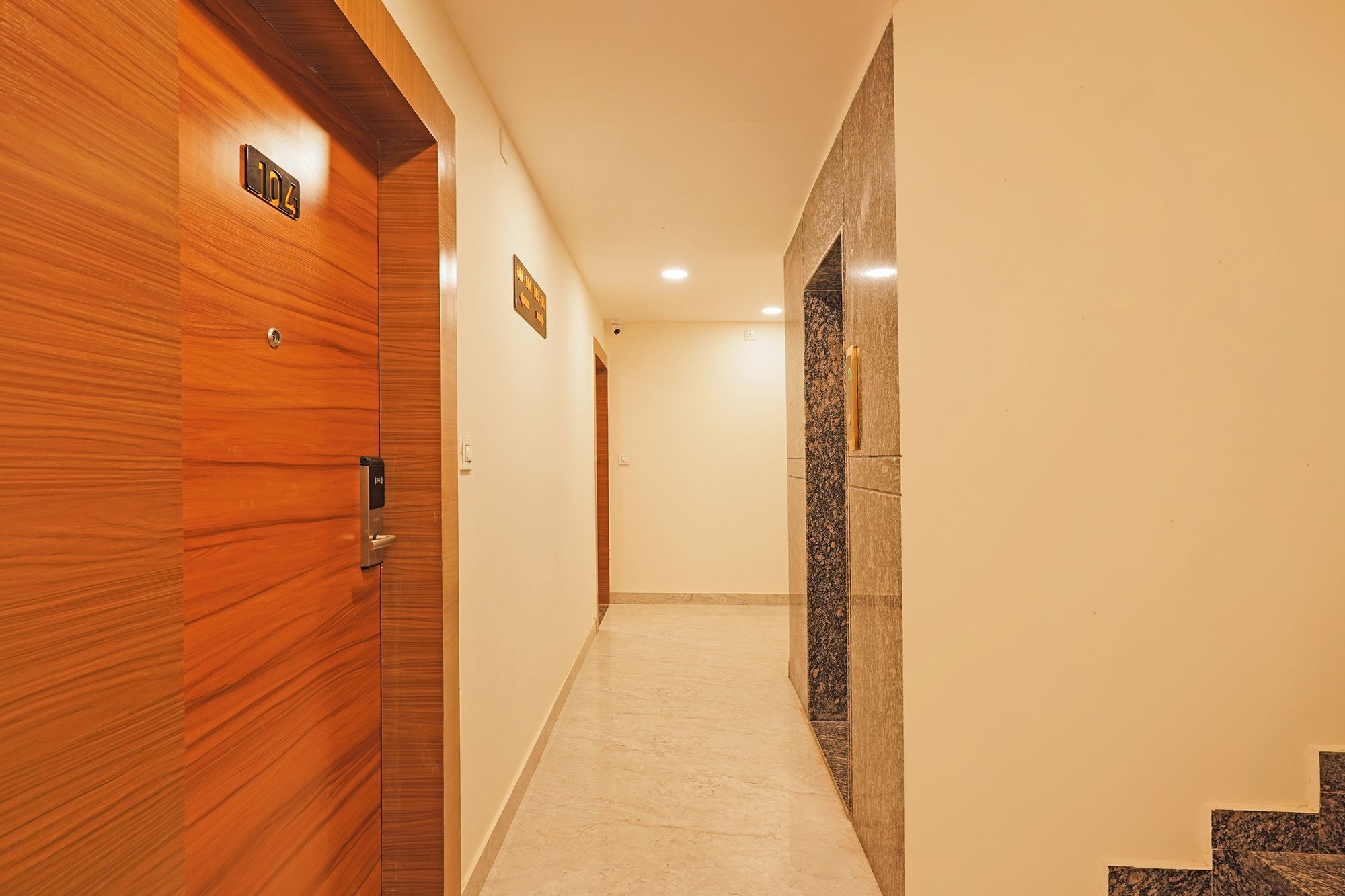Un pasillo con puertas de madera, suelo de mármol y pared de granito.
