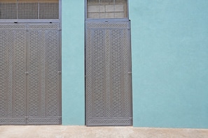 Two metal gates with intricate patterns, attached to a light blue wall. - FabHotel Hk Comfort Inn (Bangalore)