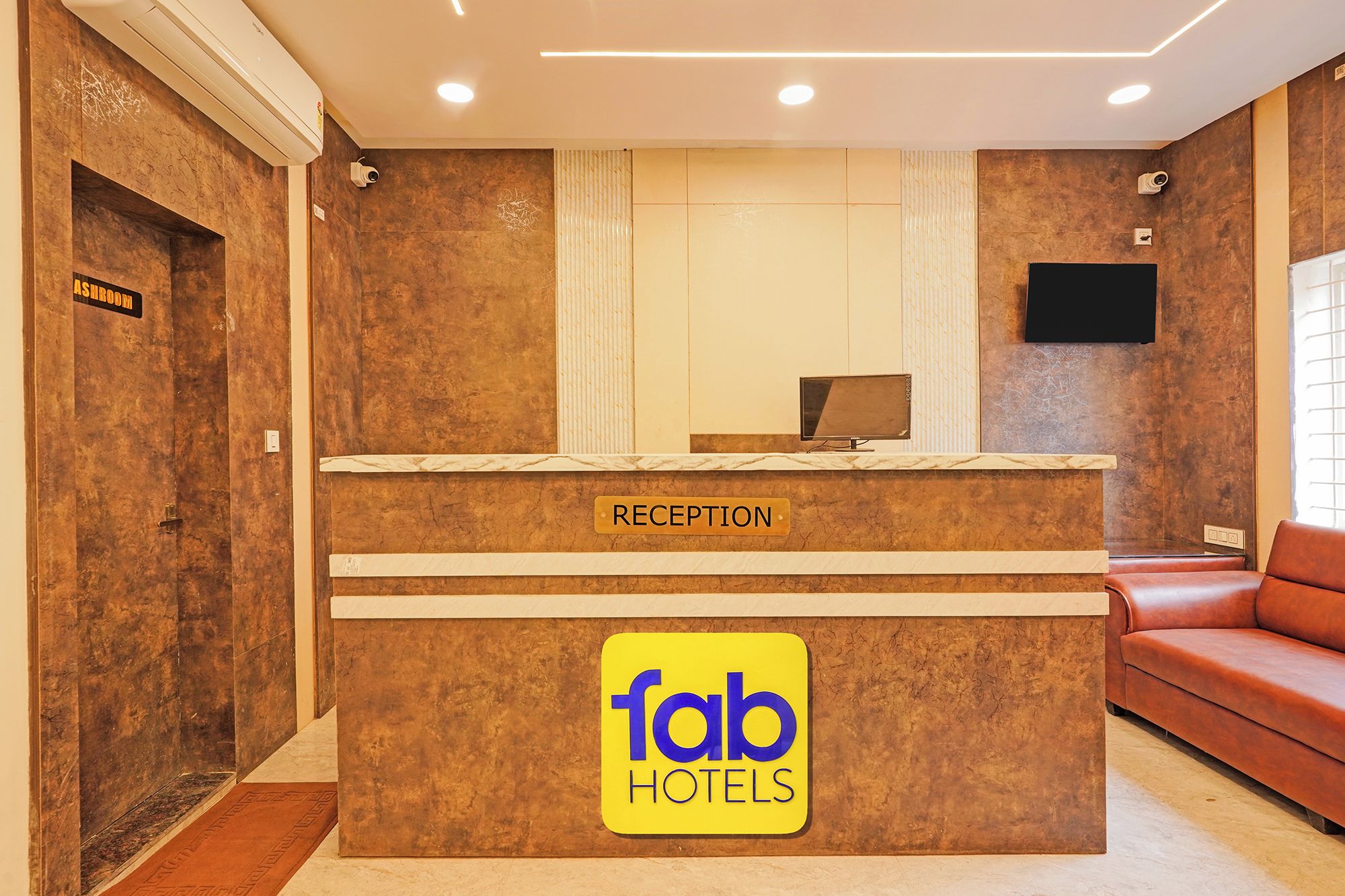 A reception desk with a sign for 'fab hotels' and a television above it.