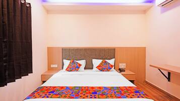 Een hotelkamer met een bed, twee nachtkastjes, een houten hoofdbord en een raam met gordijnen.