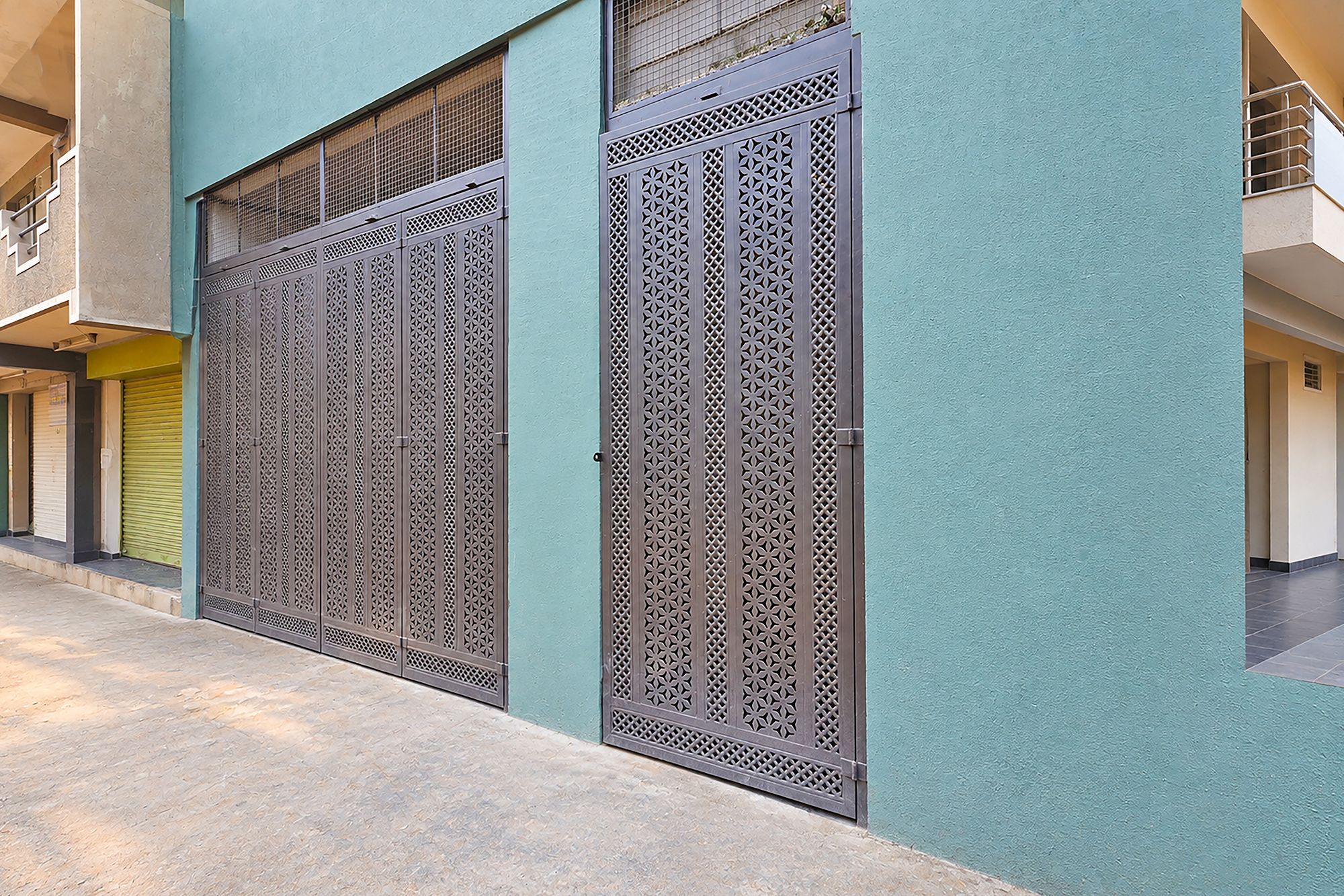 Un edificio con dos grandes portones metálicos decorados con diseños intrincados, techo plano y fachada sencilla.