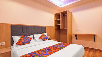 A neatly made bed with a patterned bed runner, a headboard, and a built-in wooden shelf unit to the right.