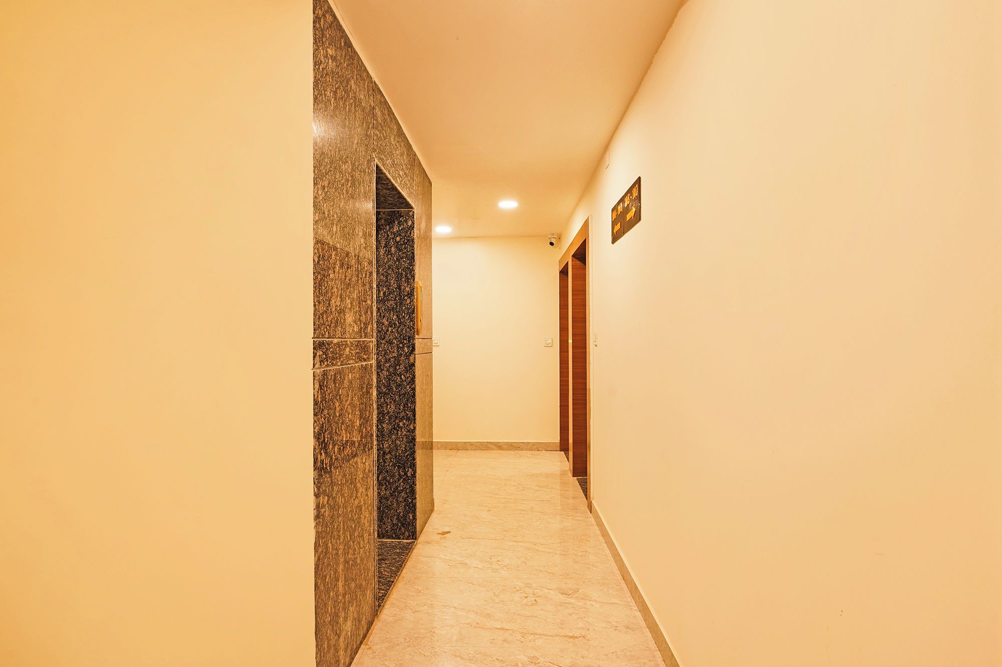 A corridor with a marble wall and a wooden door.