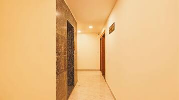 A corridor with a marble wall and a wooden door.