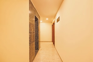 A corridor with a marble wall and a wooden door. - FabHotel Hk Comfort Inn (Bangalore)