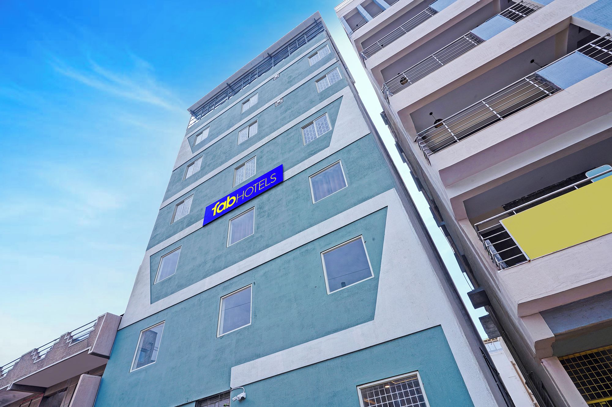 A multi-story building with a sign for 'fabHOTELS' indicating a hotel presence.