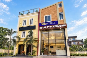 Un moderno edificio de hotel con un cartel llamativo que dice 'fabHOTELS HOTEL STAY VENUE INN'.