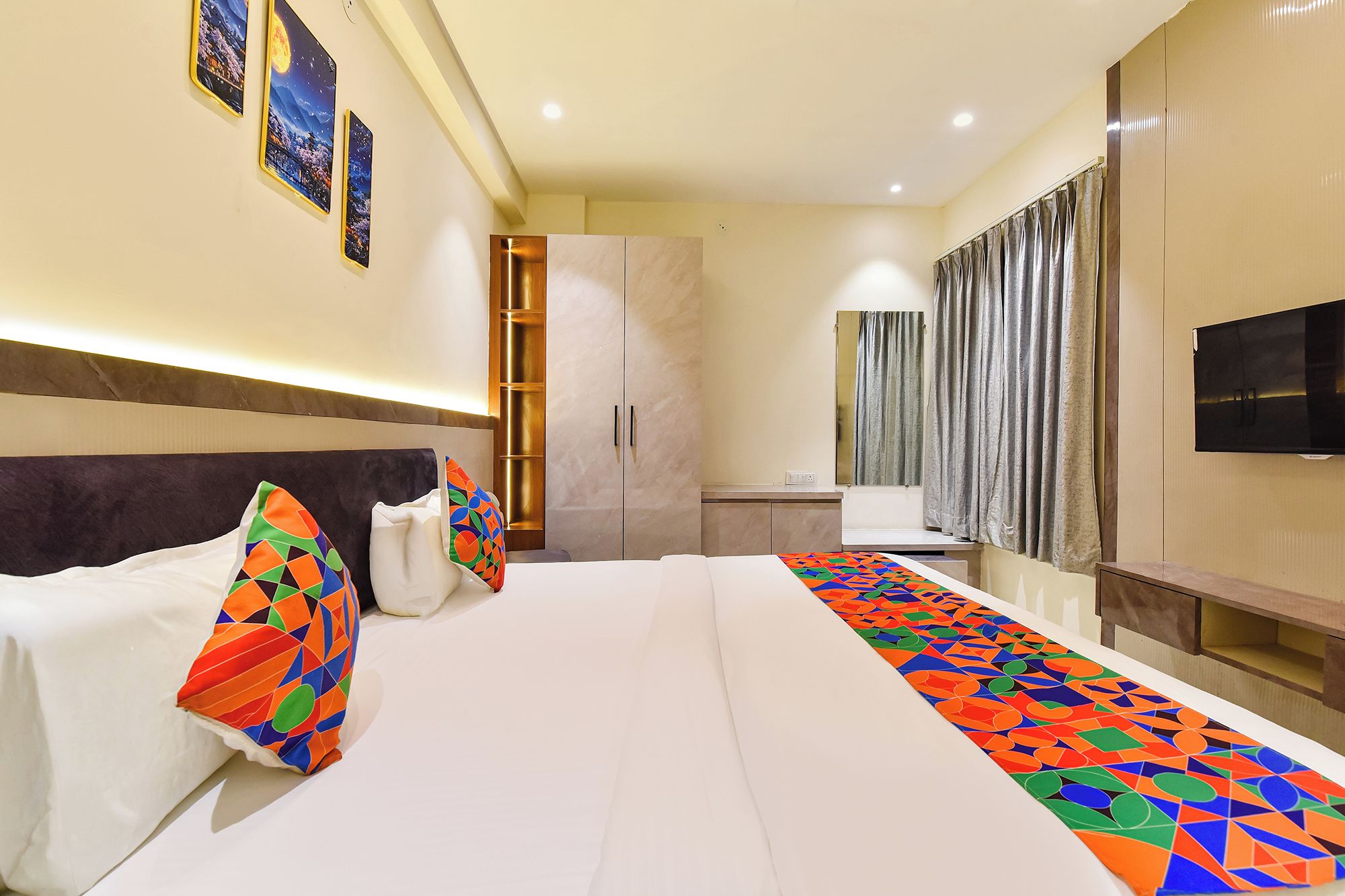 Quarto de hotel com cama, escrivaninha, televisão e banheiro.