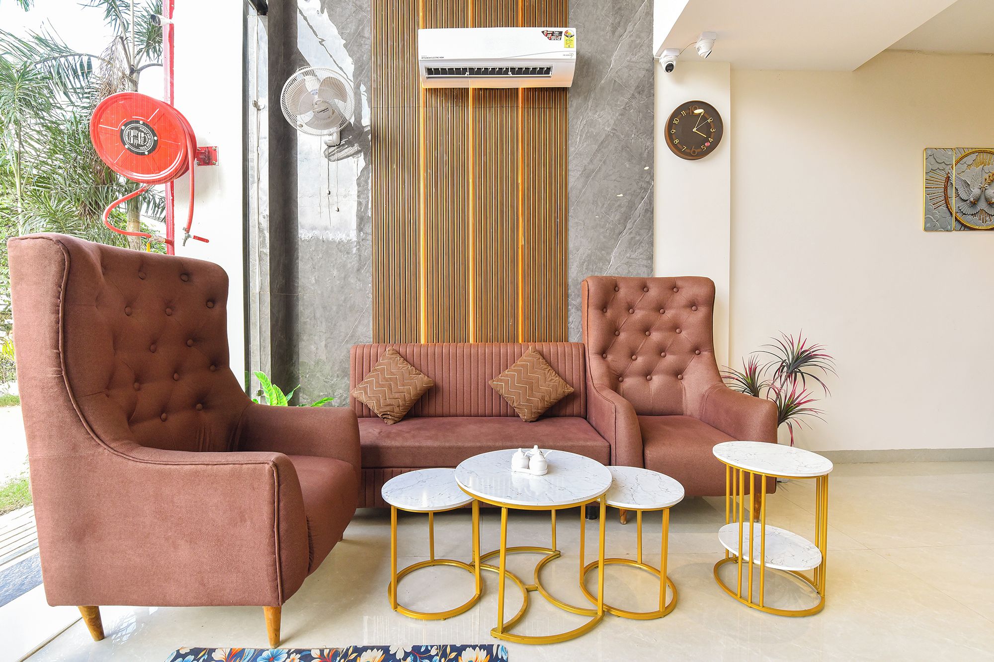 Una sala de estar moderna con un sofá, dos sillones y tres mesas redondas.