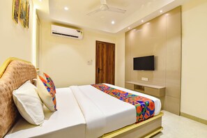 Habitación de hotel con cama, televisión de pantalla plana, equipo de aire acondicionado y ventilador de techo.