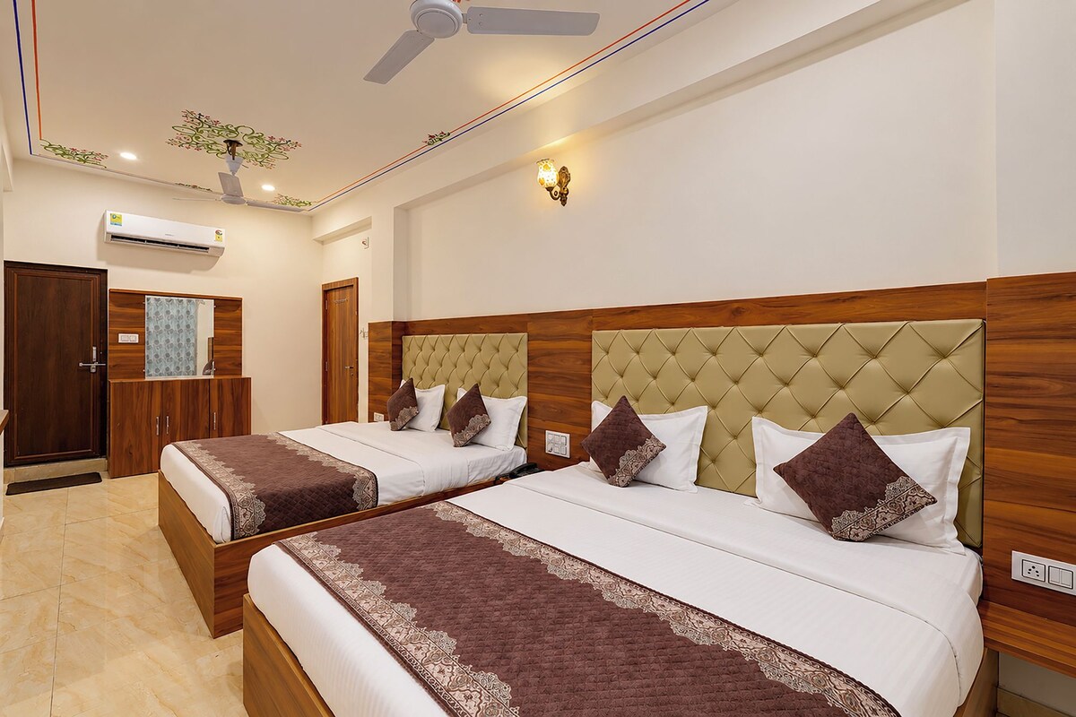 Habitación de hotel con dos camas, ventilador de techo, aire acondicionado, un espejo y una puerta.