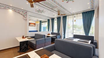 Ein modernes Hotelzimmer mit einer Sitzecke, einem Esstisch und einem Deckenventilator.