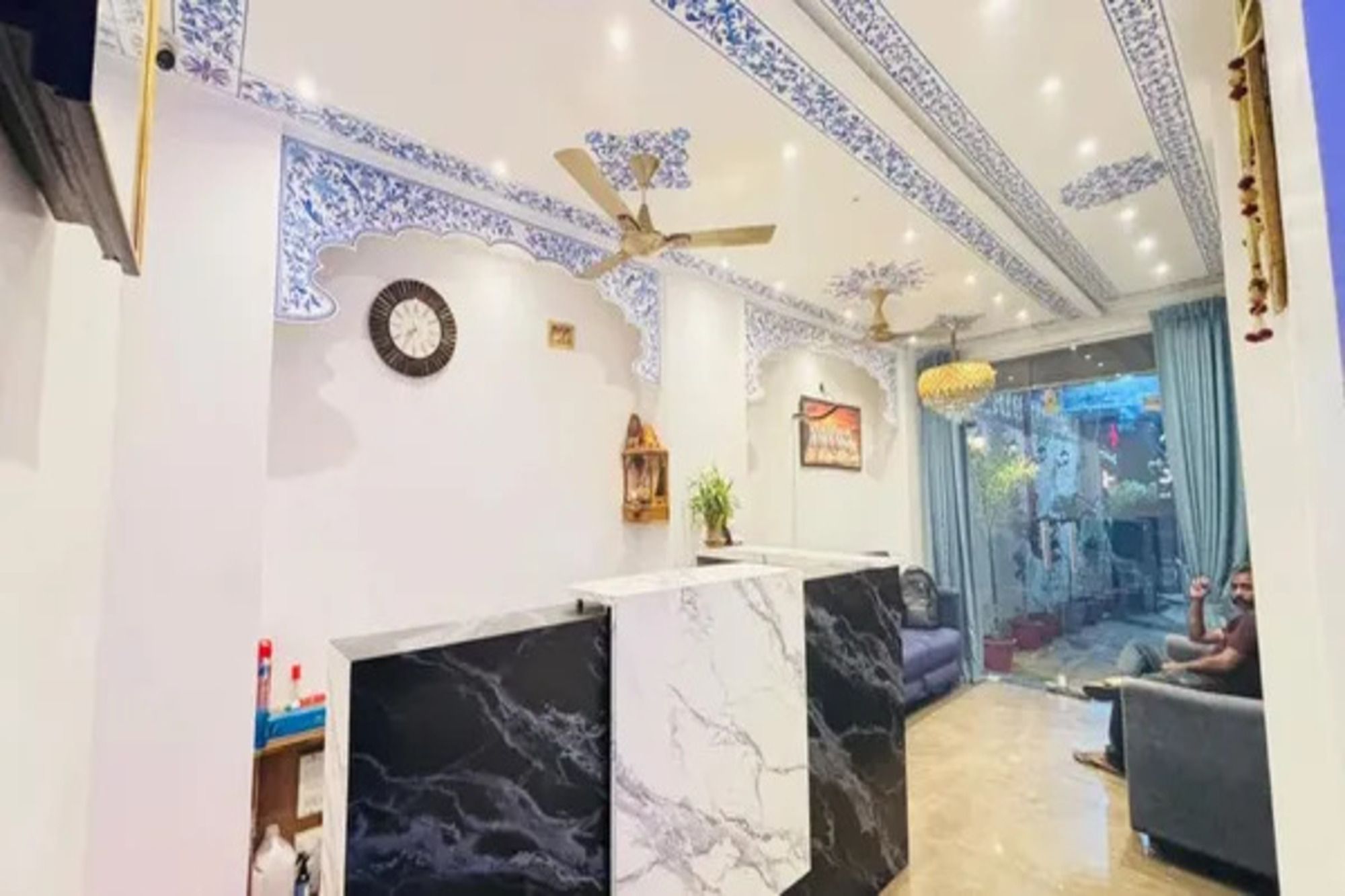 A hotel lobby with a reception desk, seating area, decorative ceiling, and a view of the outside.