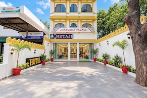 Entrada de un hotel con un letrero que dice 'Jharokha Palace' y 'Netaji' hotel.